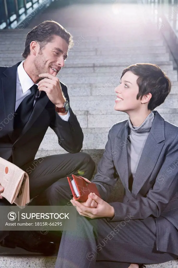 Germany, Bavaria, Munich, Business man and business woman sitting on staircase at underground station