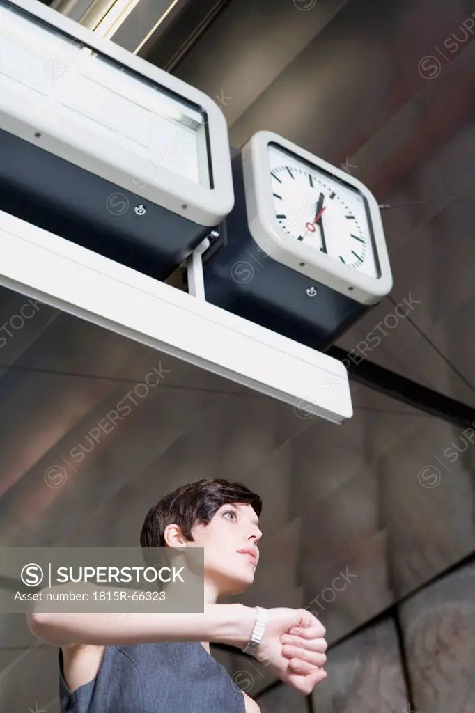 Germany, Bavaria, Munich, Business woman at subway station looking at wrist watch