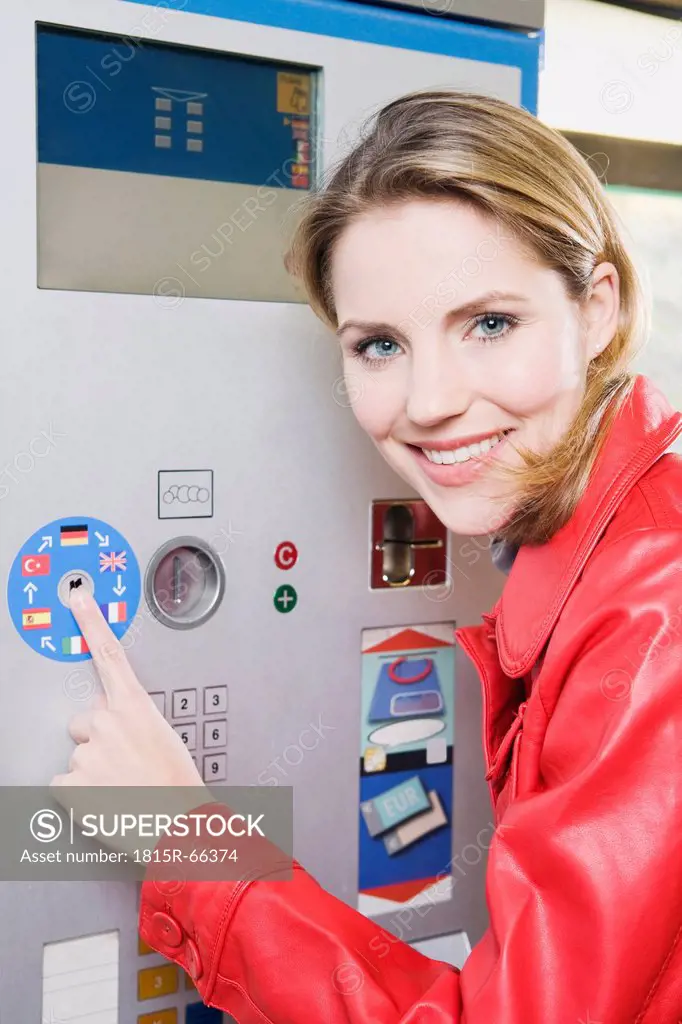 Germany, Bavaria, Munich, Young woman at ticket machine in subway station, smiling, portrait, close_up