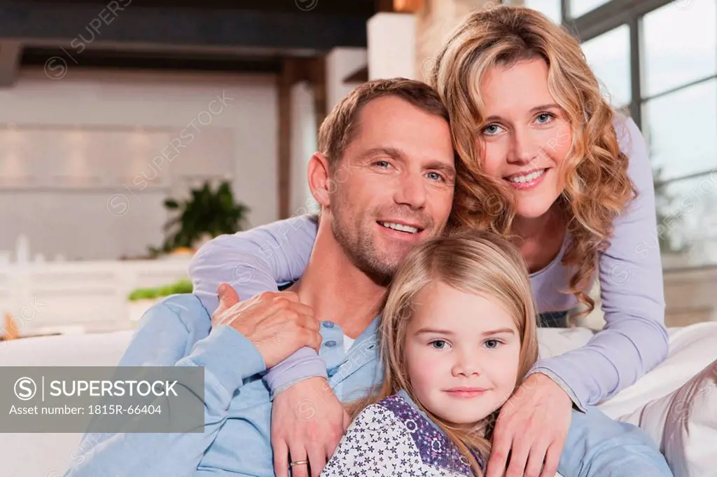 Germany, Cologne, Family sitting on sofa, smiling, portrait, close_up