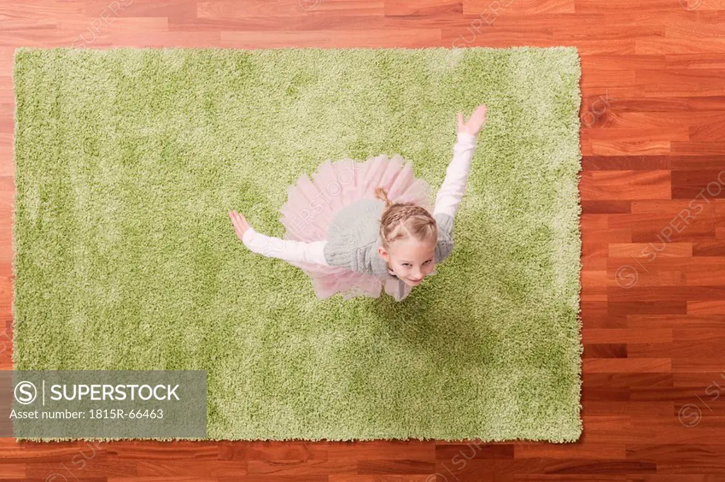 Germany, Cologne, Girl 6_7 playing on carpet, looking up, elevated view