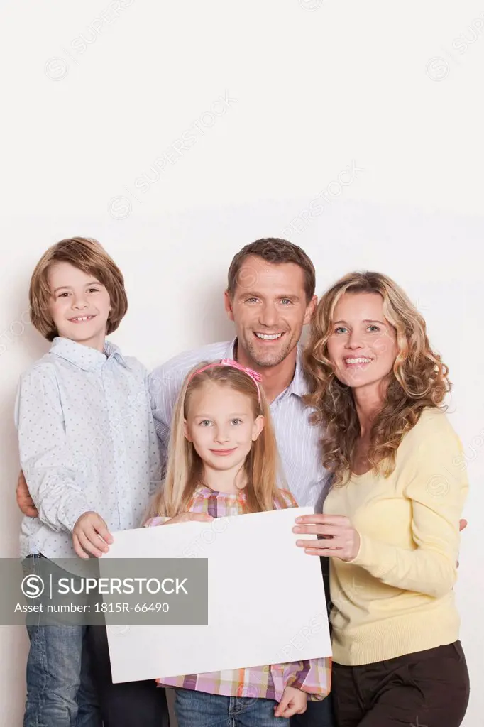 Germany, Cologne, Family holding blank carton, smiling, portrait