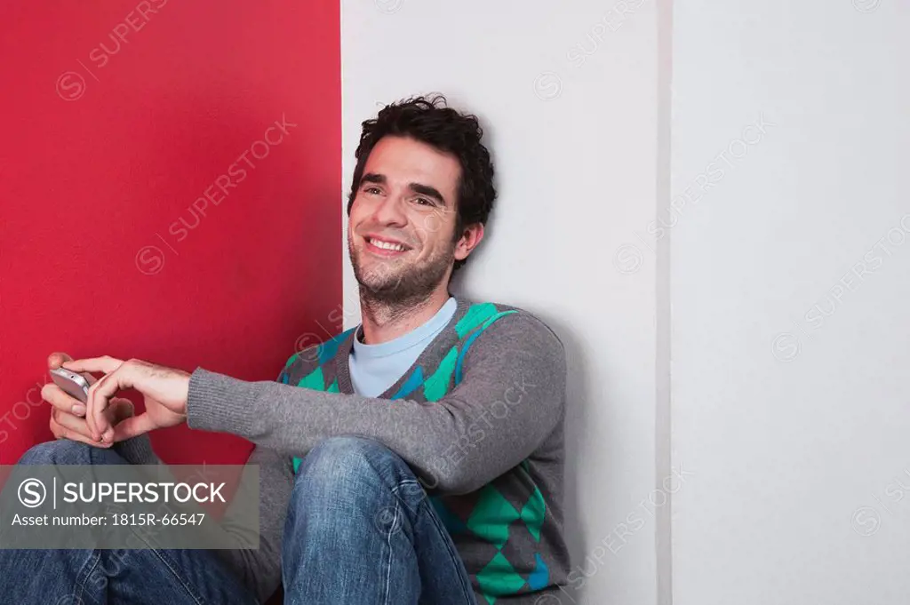 Man holding mobile phone, smiling