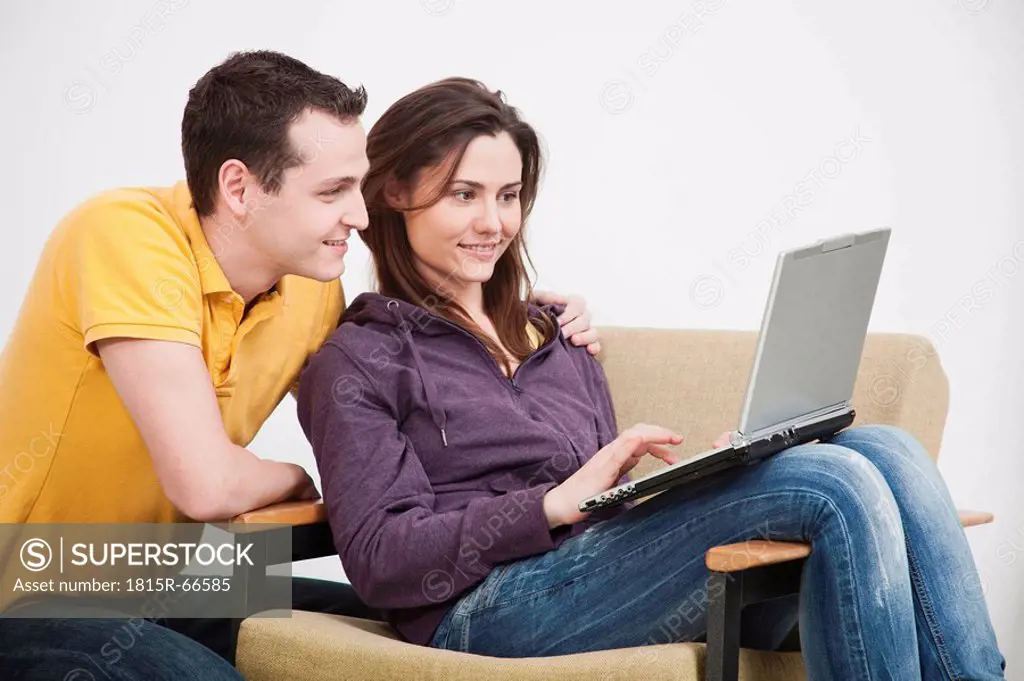 Young couple using laptop, smiling.