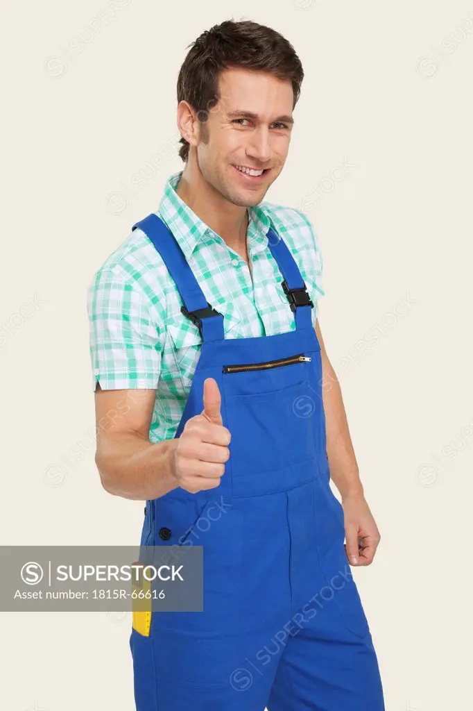 Man in overall showing thumbs up sign, smiling, portrait