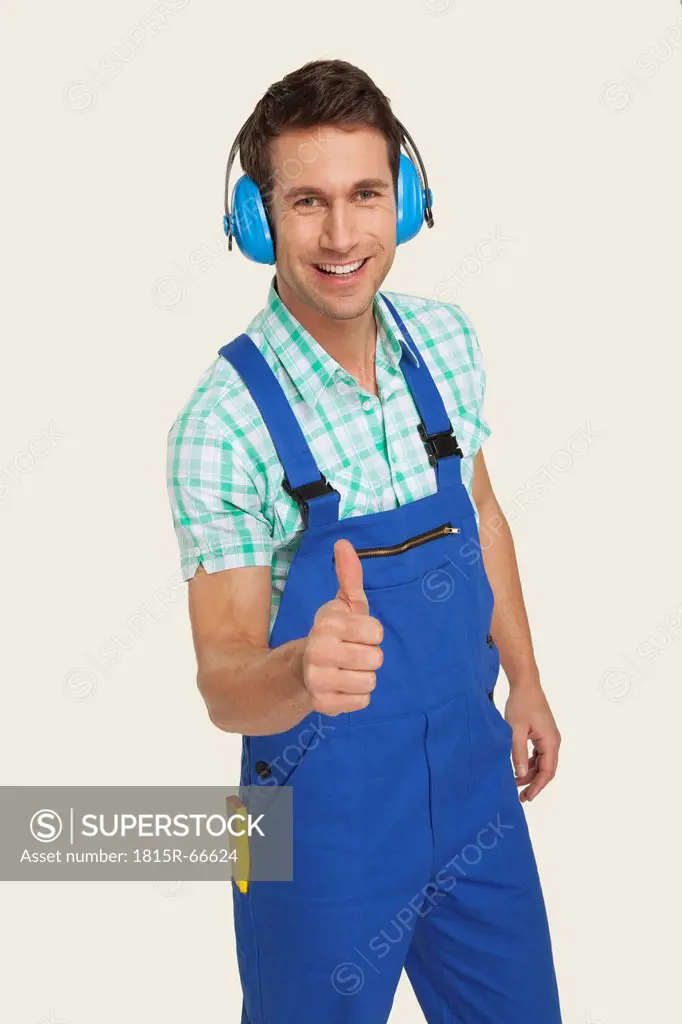 Man wearing ear muff showing thumbs up sign, smiling, portrait