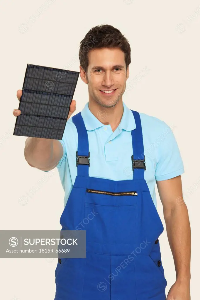 Man holding solar cell, smiling, portrait