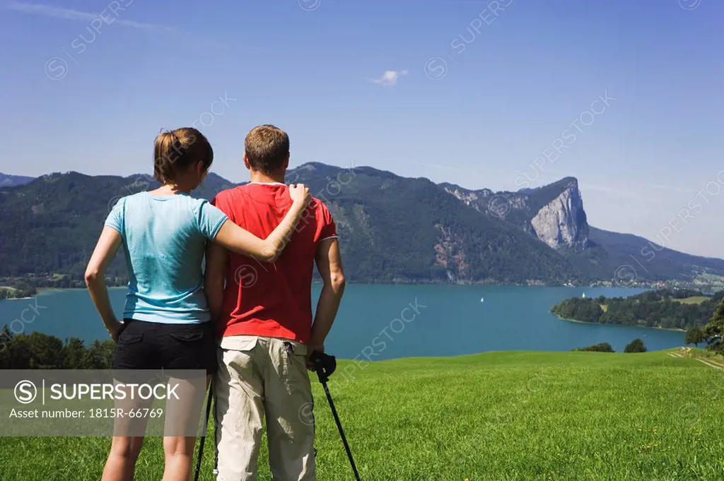 Austria, Lake Mondsee, Young couple looking at lake, rear view