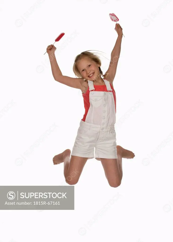 Girl 10_11 holding lollypops, jumping in air, smiling, portrait