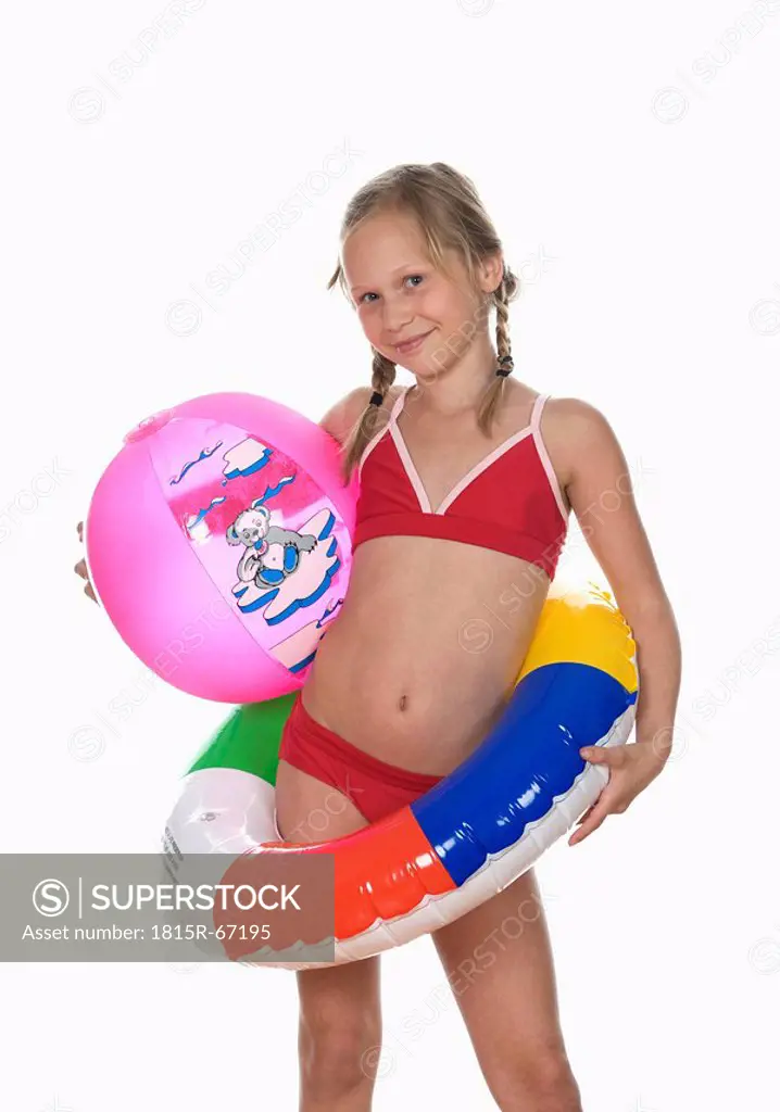 Girl 10_11 wearing bikini, holding floating tire and beachball