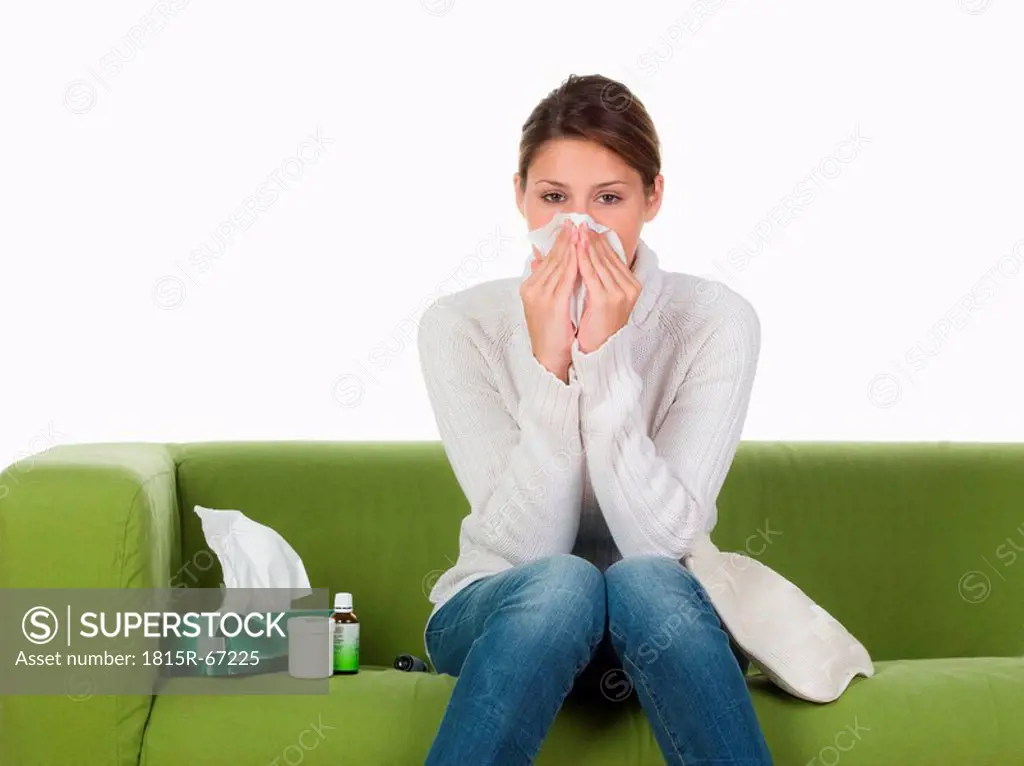 Young woman on sofa blowing nose