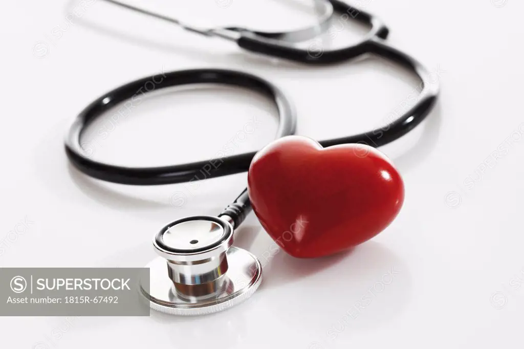 Stethoscope with heart shape object on white background, close up