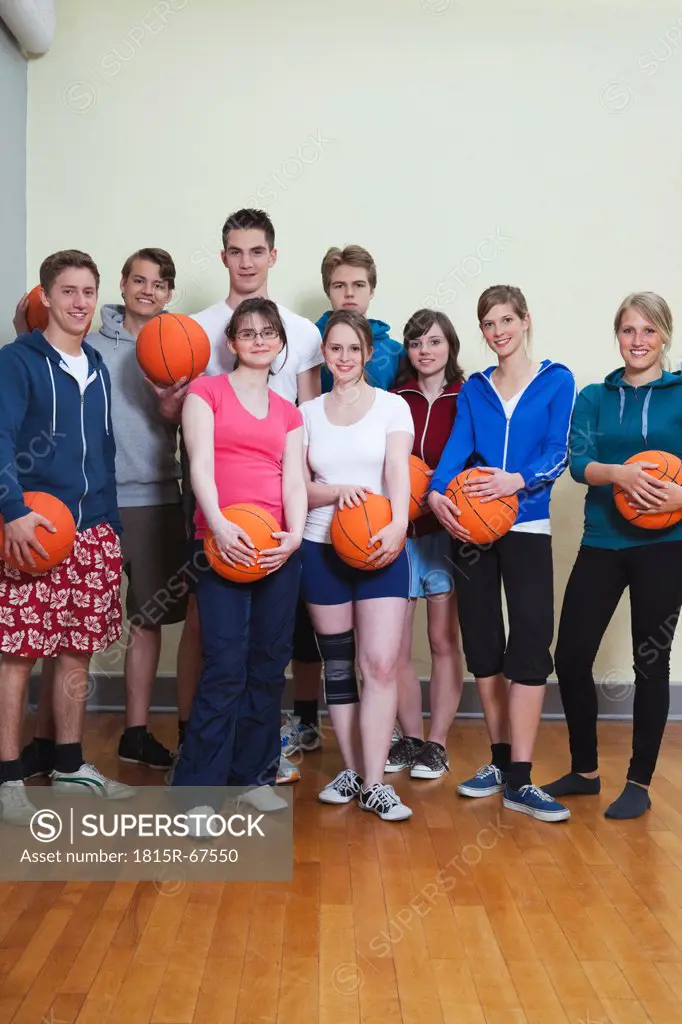 Germany, Berlin, People standing and holding basketball, portrait