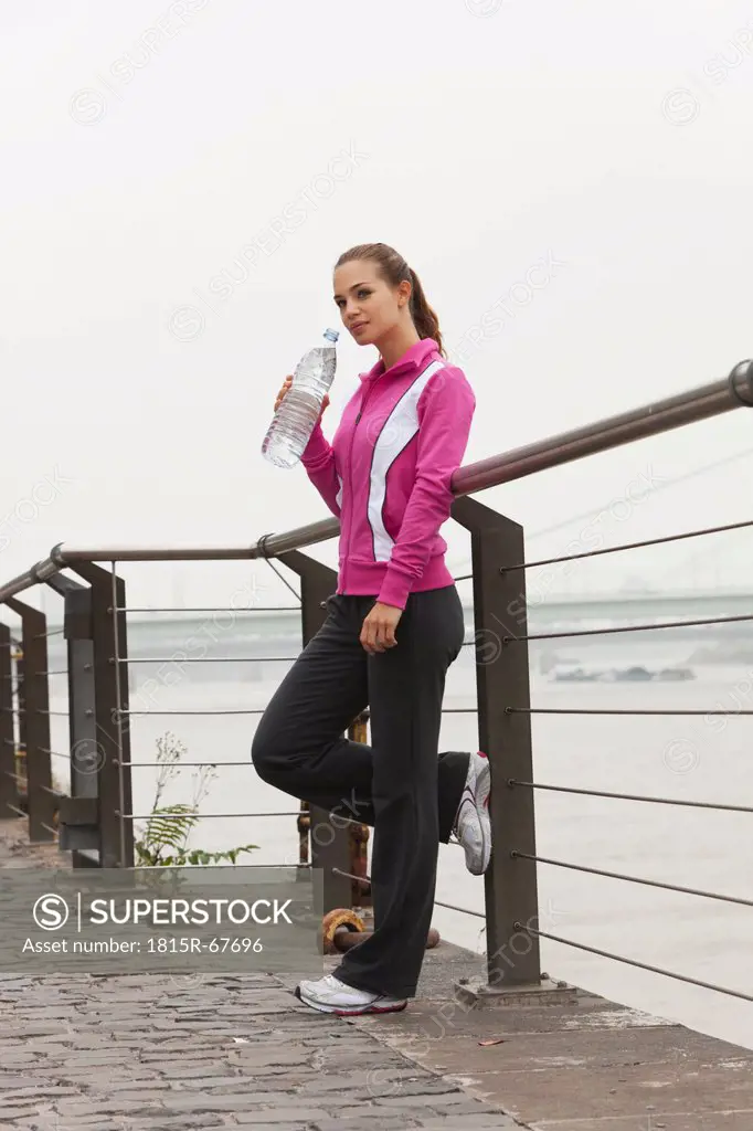 Germany, Cologne, Young woman with water bottle