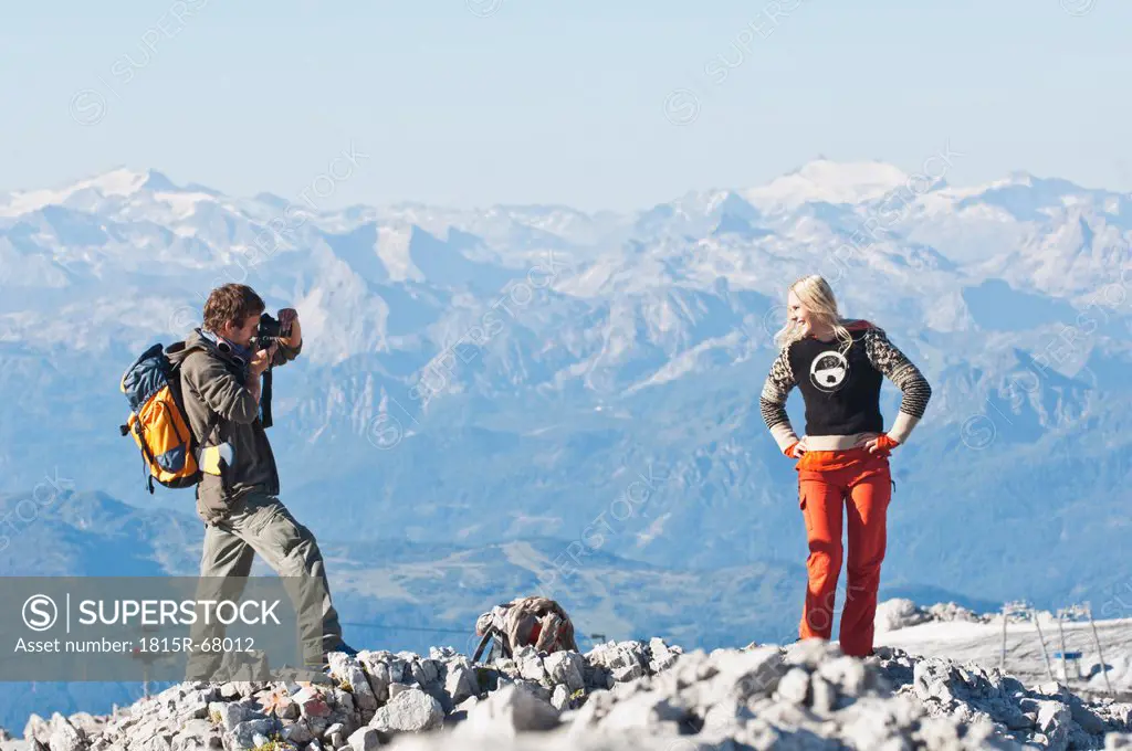 Austria, Steiermark, Dachstein, Man taking photograph of woman on mountain top