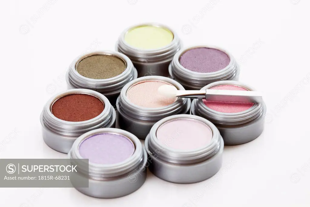 Multi coloured eye shadows with make up brush on white background