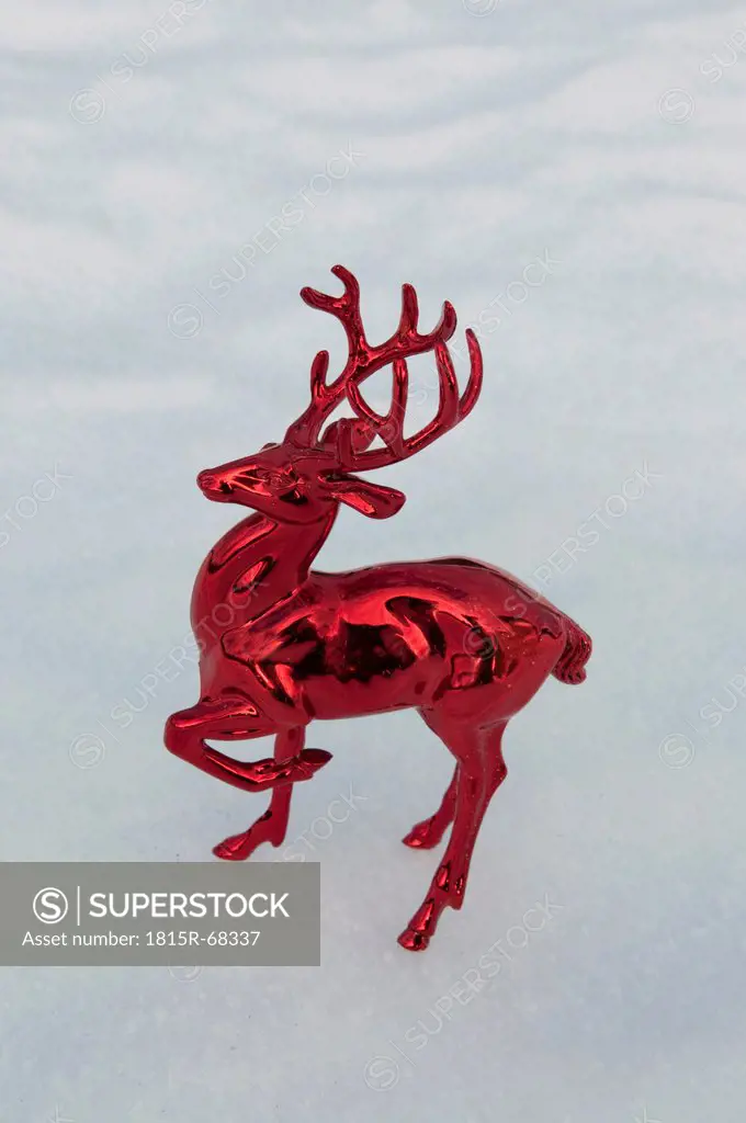 Shiny plastic stag standing in snow, winter.