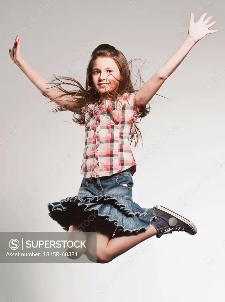 Girl 8_9 jumping with arms up, smiling