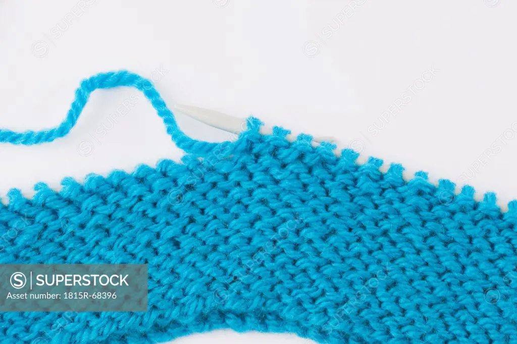 Blue knitting wool and knitting needles on white background