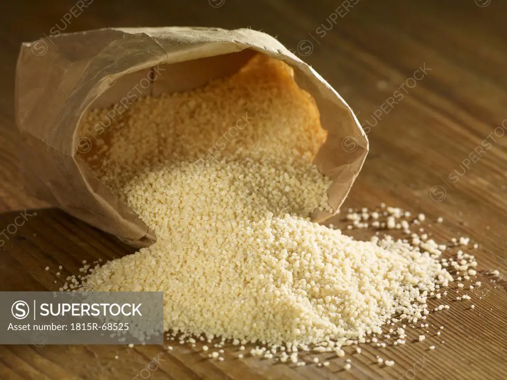 Couscous spilling on wooden surface