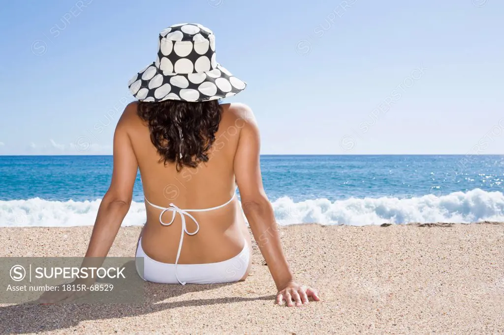 France, Corsica, Woman relaxing on beach, rear view