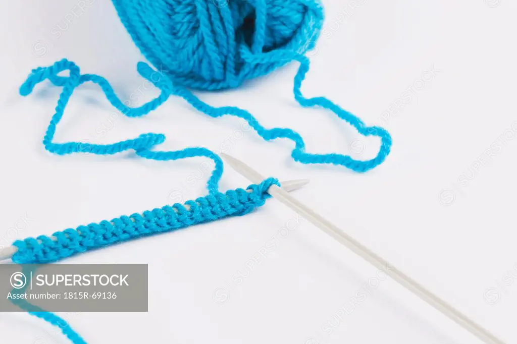 Blue knitting wool and knitting needles on white background