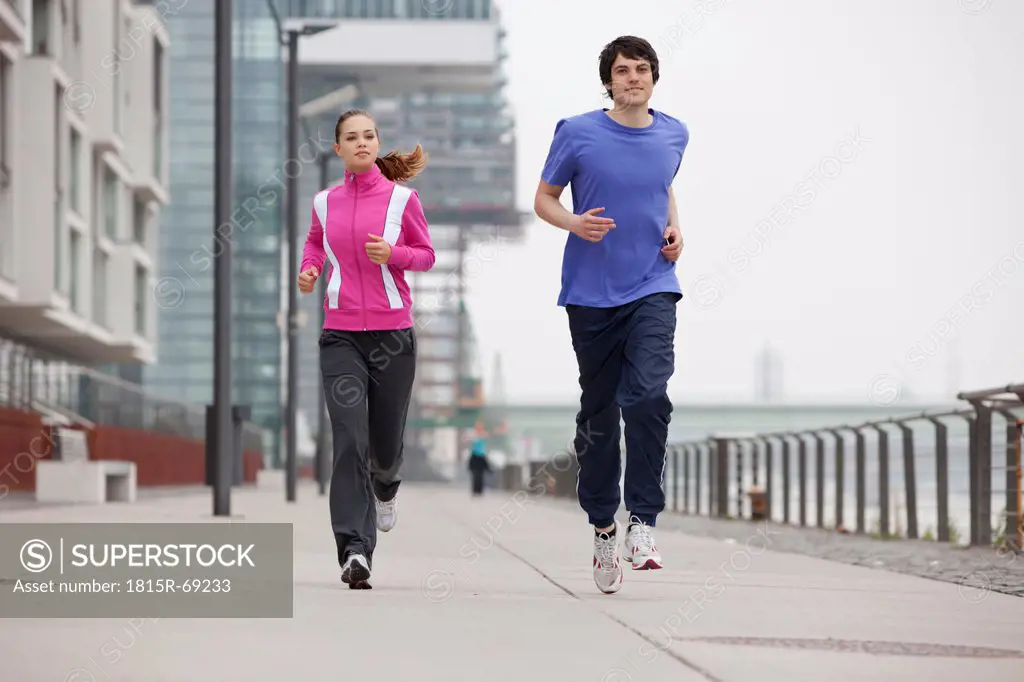 Germany, Cologne, Young man and woman jogging