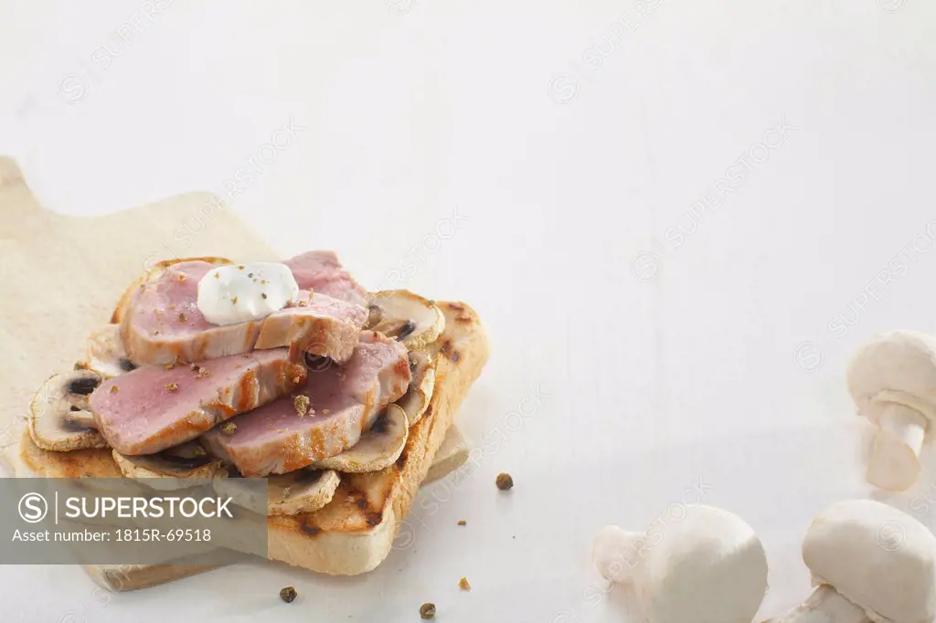 Pork filet sandwich with mushrooms and creme fraiche on white background, close_up