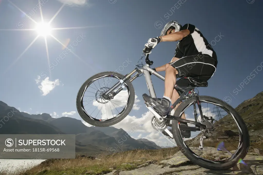 Switzerland, Tessin, Man doing stunt on mountain bike