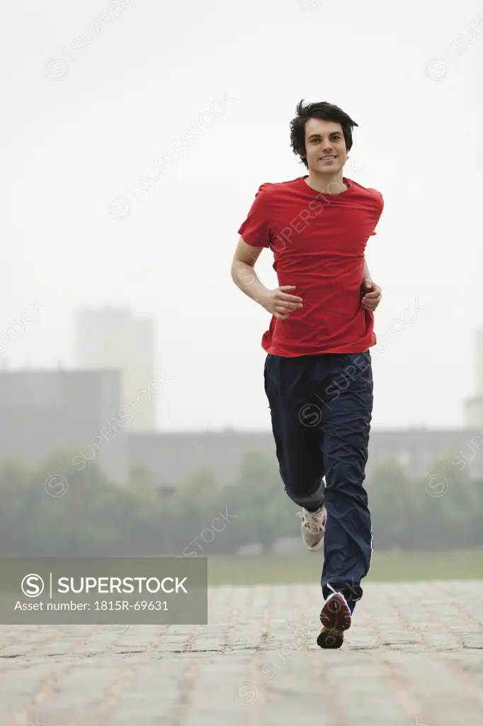 Germany, Cologne, Young man jogging, smiling