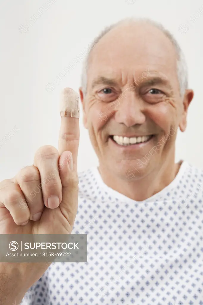 Germany, Munich, Mature man showing finger with bandage, close_up