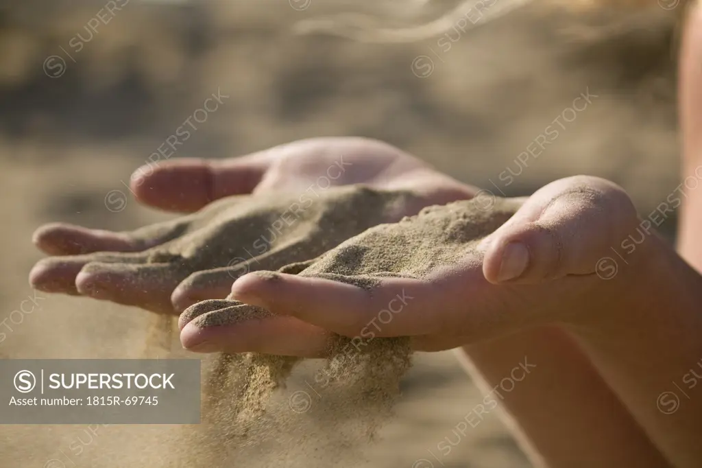 Italy, Jesolo, Teenage girl playing with sand on beach
