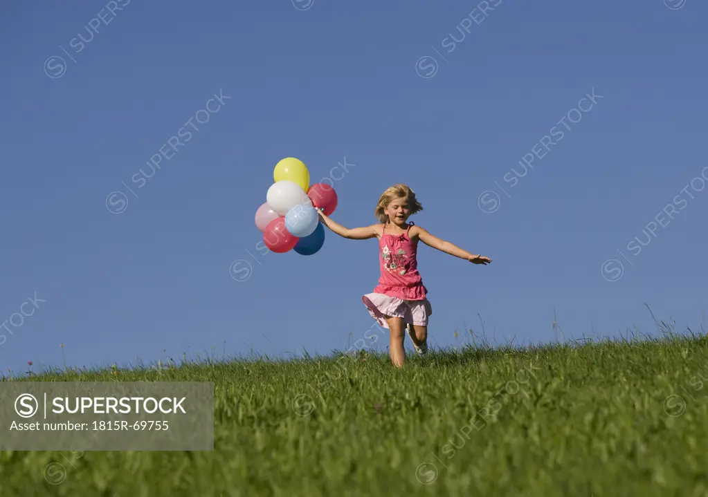 Austria, Mondsee, Girl 4_5 running through meadow holding balloons