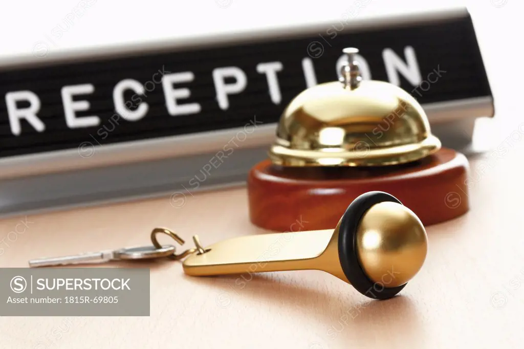 Reception sign with service bell and hotel key on desk