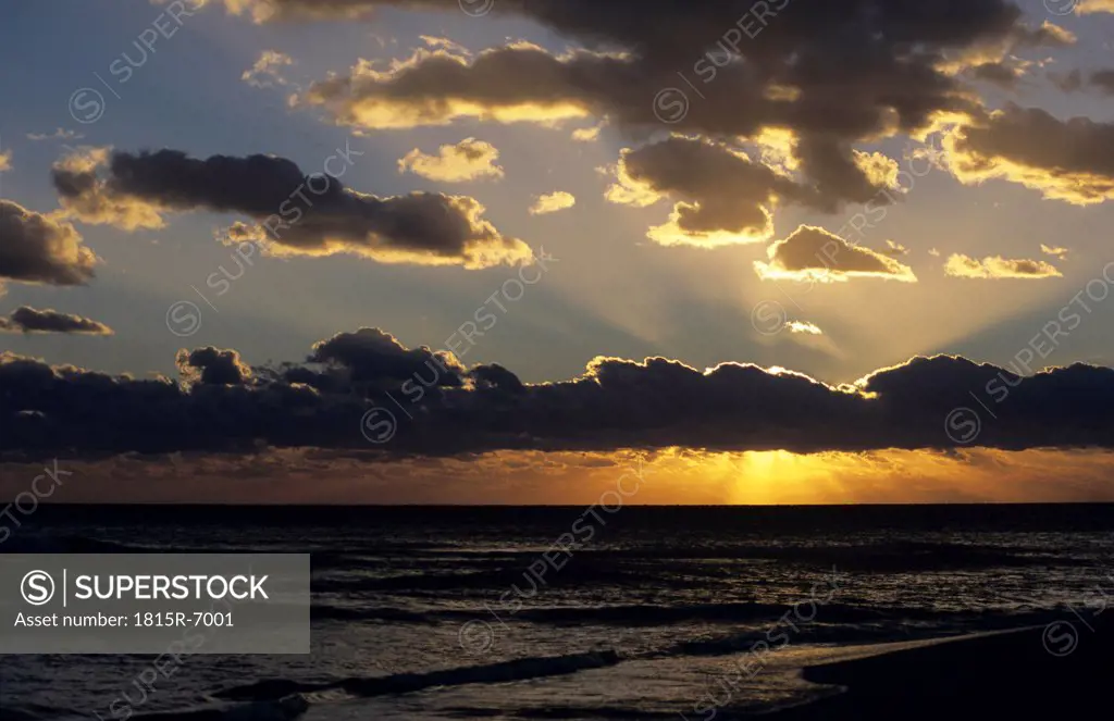 Italy, Apulia, Sun shining through clouds at sunset
