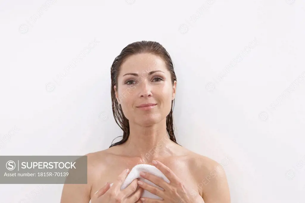 Germany, Woman in bathroom holding towel, smiling