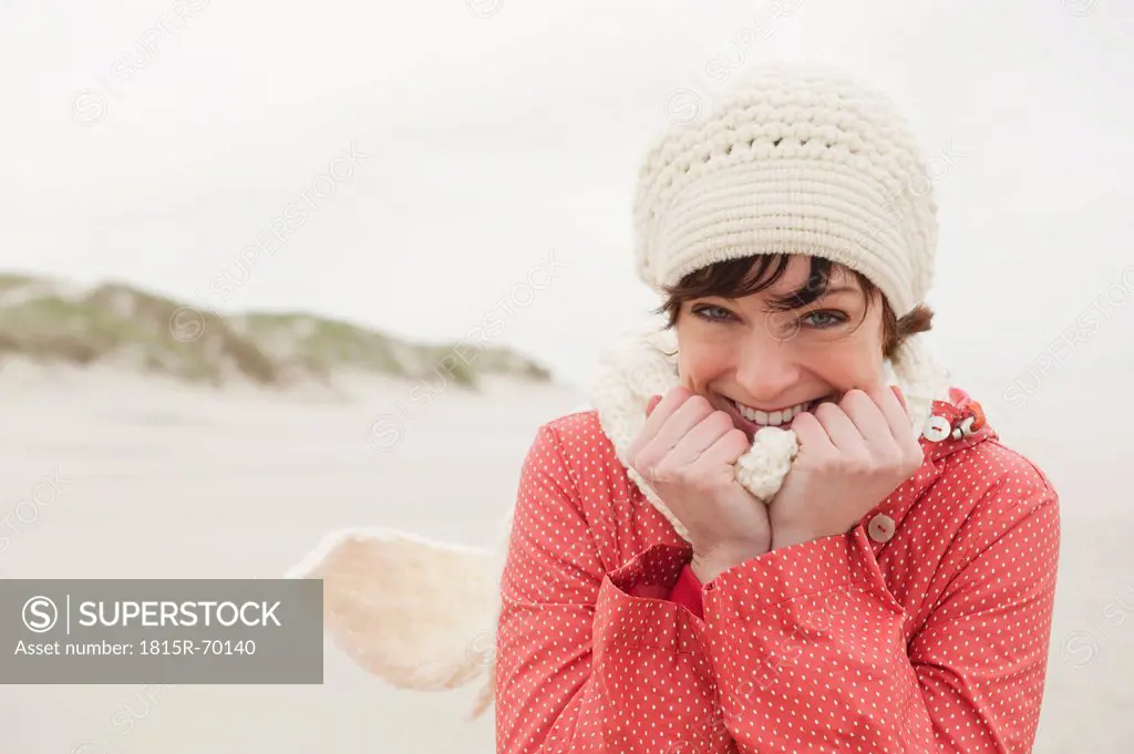 Germany, St Peter_Ording, North sea, Woman having fun in sand dunes, smiling, portrait