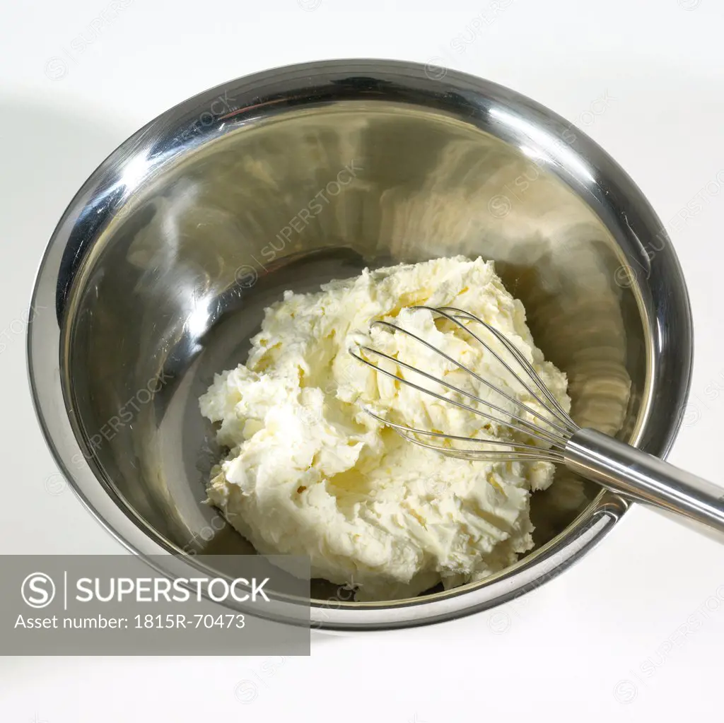 Cheese in bowl with beater on white background