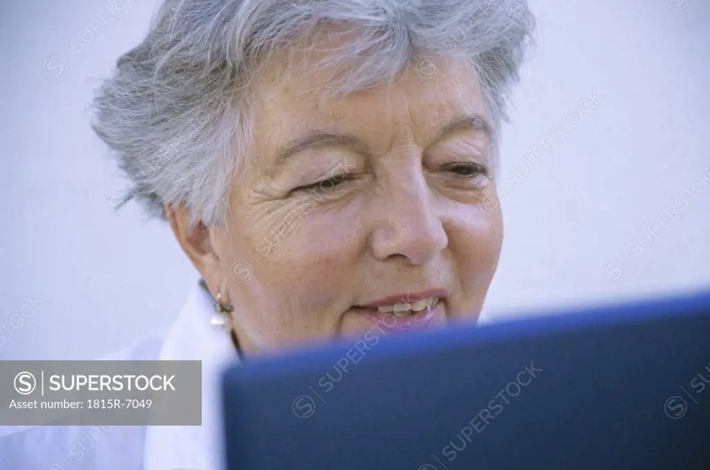 Senior woman using laptop, smiling