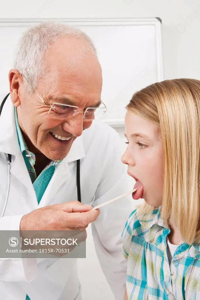 Germany, Munich, Doctor examining girl 8_9 with tongue depressor