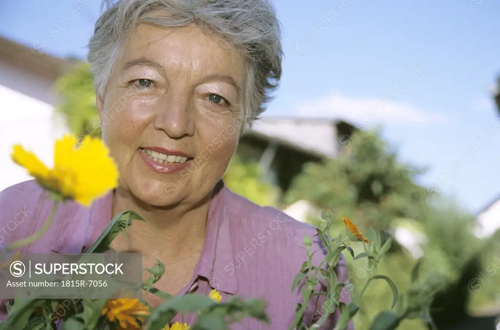 Senior woman in front of flowers, low angle view