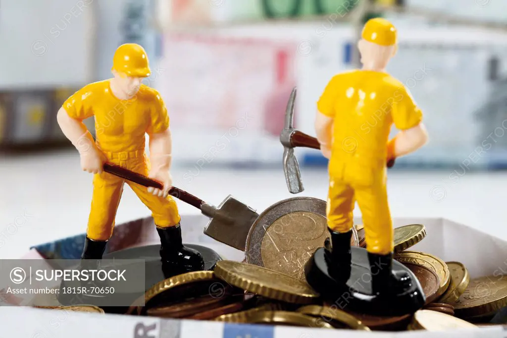 Figurine workers standing on pile of euro coins holding shovel and hammer