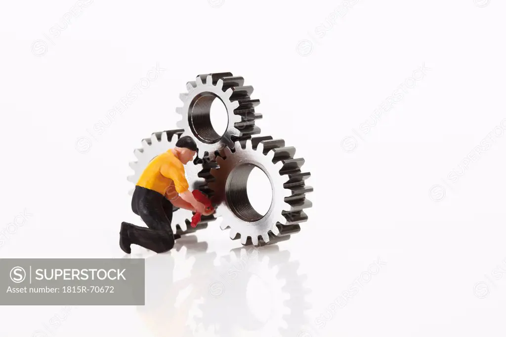 Worker figurine with cogwheels on white background