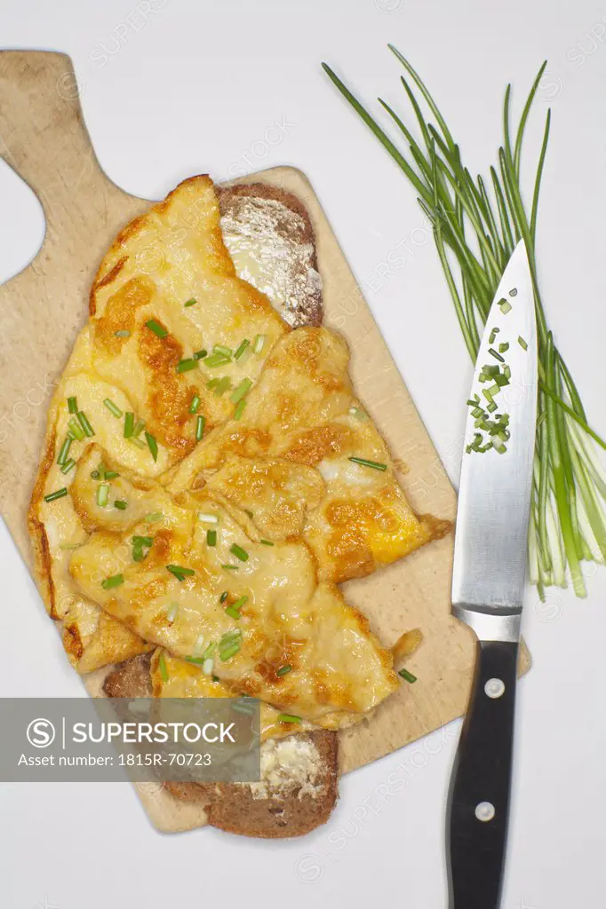 Scrambled eggs garnished with chive on chopping board.