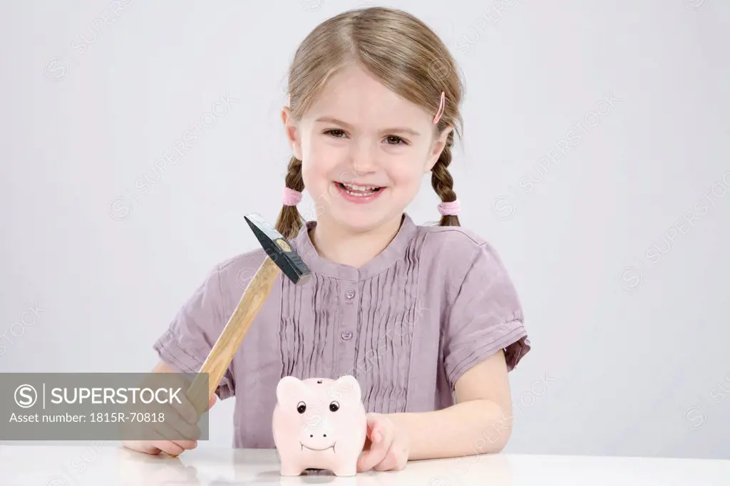 Girl 4_5 with a hammer is about to break a piggybank