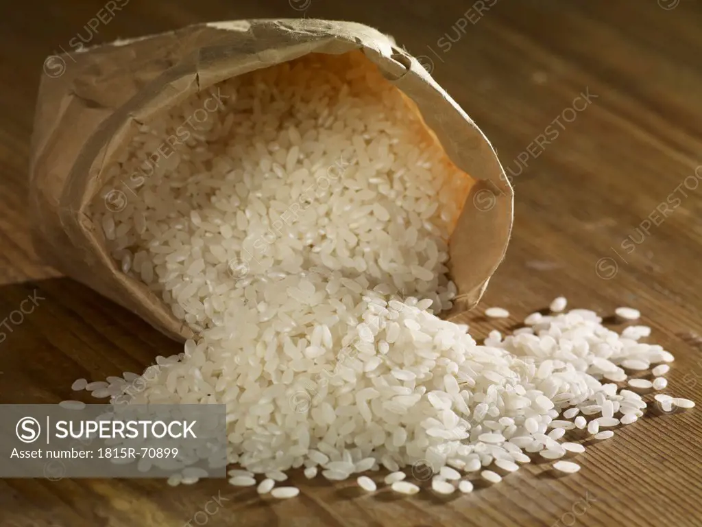 Round corn rice spilling on wooden surface