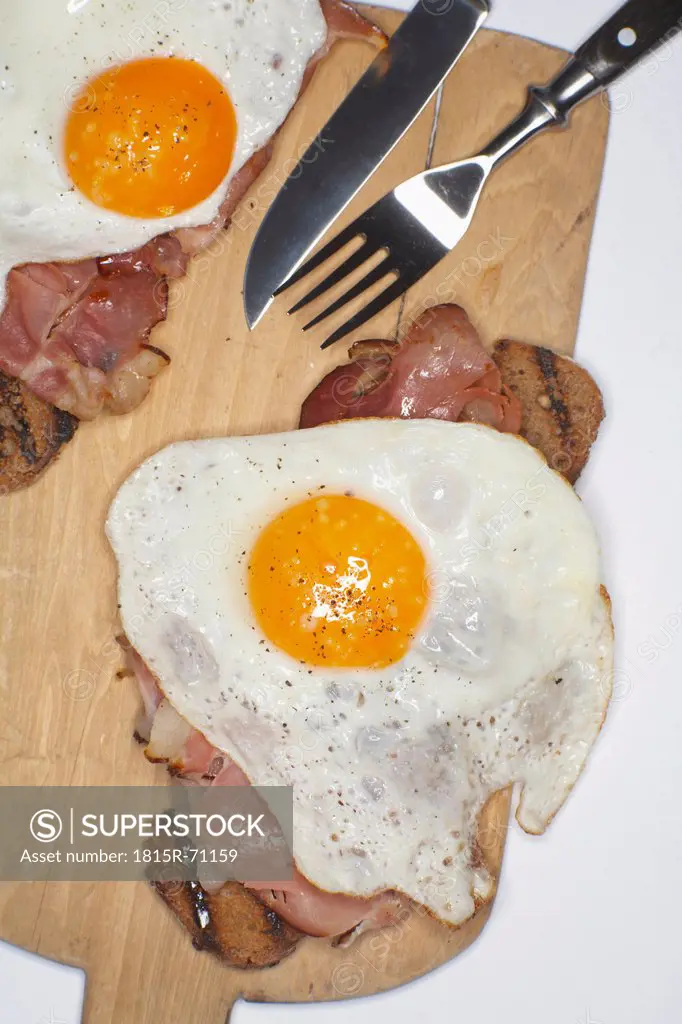 Fried egg and ham on chopping board.