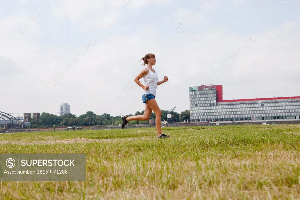 Germany, Cologne, Young woman jogging