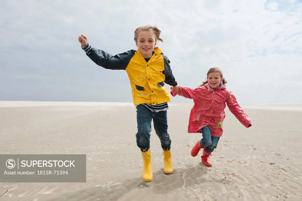 Germany, St. Peter_Ording, North Sea, Children 6_9 holding hands and running on beach
