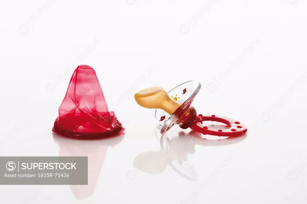 Condom and pacifier on white background